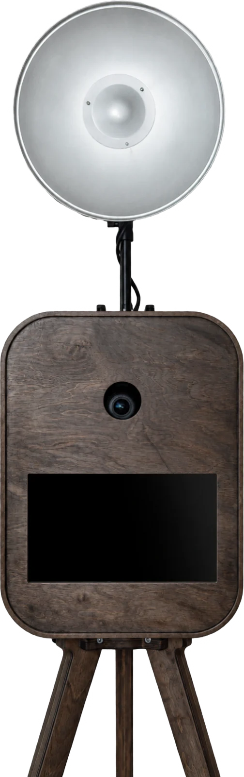 Dunkle Fotobox aus gebeiztem Holz mit Kameralinse, Display und silberner Beauty-Dish-Leuchte auf Holzstativ, Frontansicht.